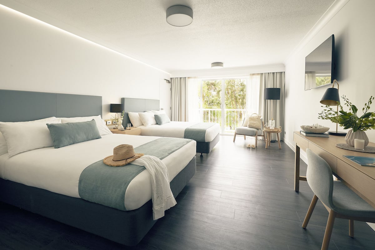 Una habitación de hotel moderna con dos camas, un escritorio y un balcón con vistas.