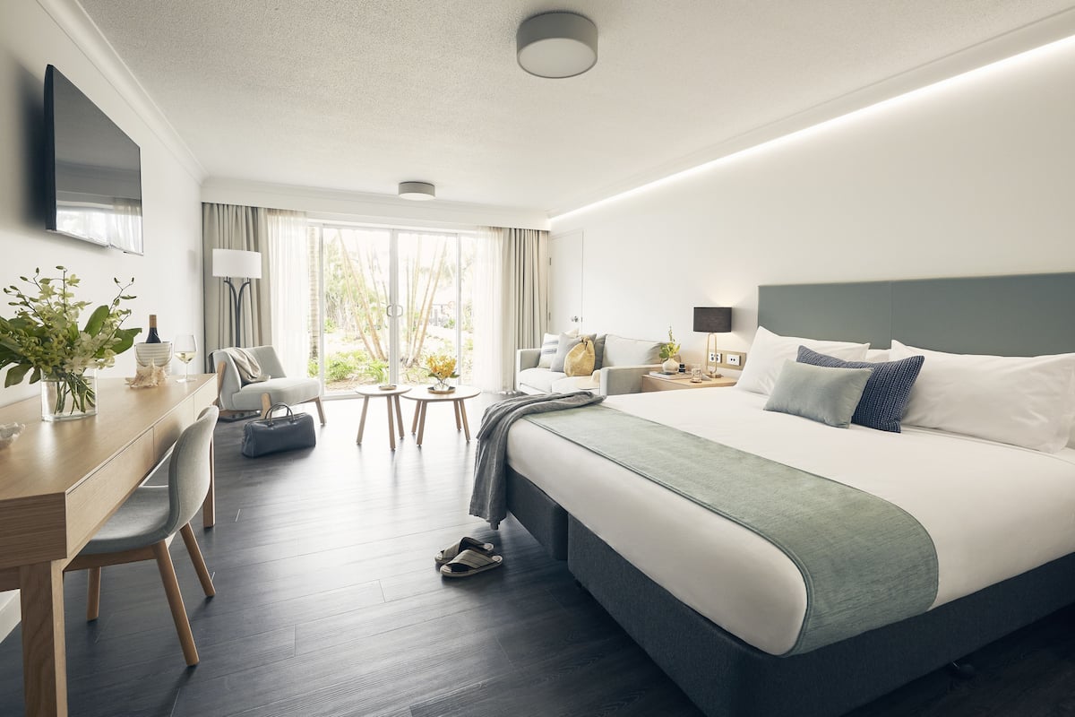 Una habitación de hotel moderna con una cama grande, un escritorio, una silla y un televisor.
