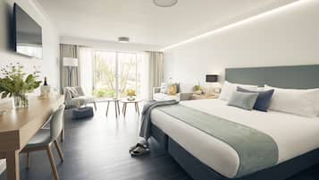 Una habitación de hotel moderna con una cama grande, un escritorio, una silla, un televisor y una ventana con cortinas.