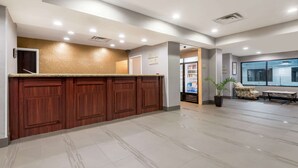 A reception area with a wooden counter, a potted plant, and a seating area with a patterned chair. - Hawthorn Extended Stay by Wyndham Columbus West (Columbus)