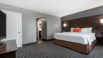 Una habitación de hotel con una cama grande, un escritorio y una puerta que da a un baño.
