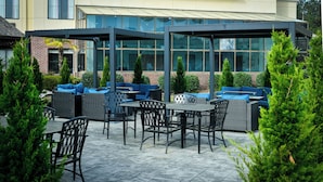 An outdoor patio area with seating arrangements and a glass building in the background.