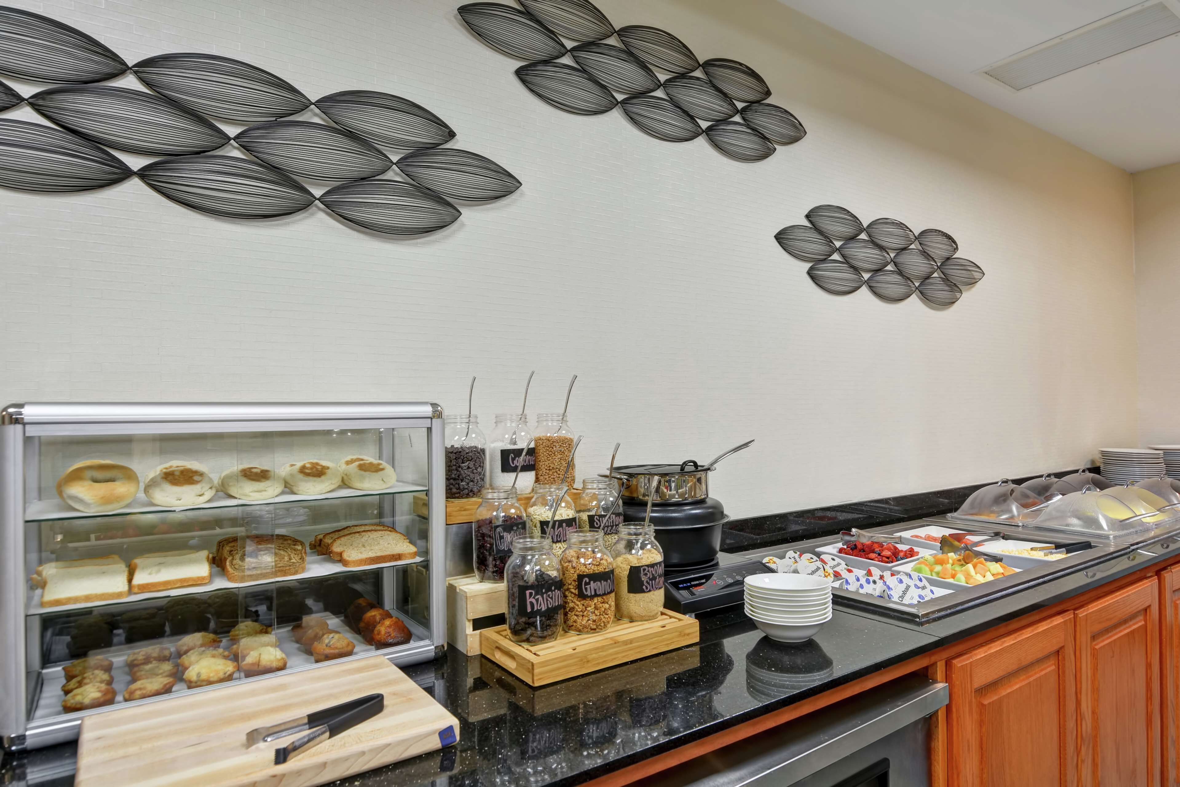 A buffet area with various food items, including pastries, cereals, and fruits.