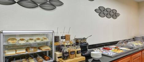 A buffet area with various food items, including pastries, cereals, and fruits.