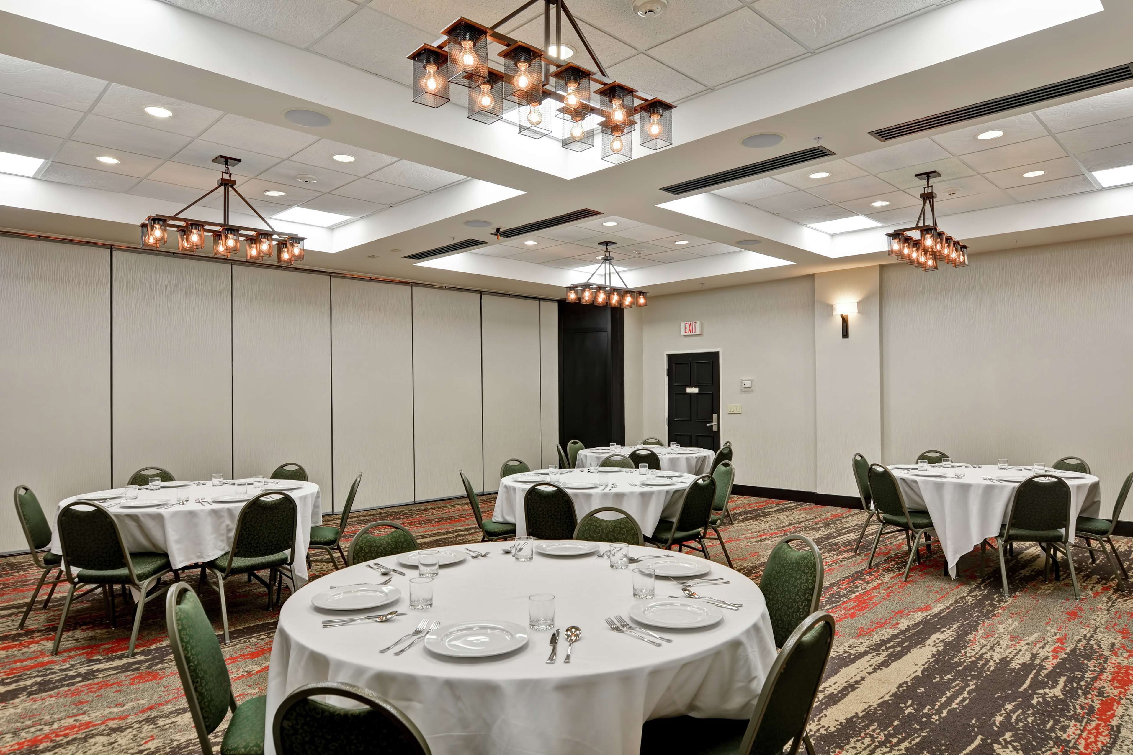 A conference room with round tables, green chairs, and a patterned carpet.