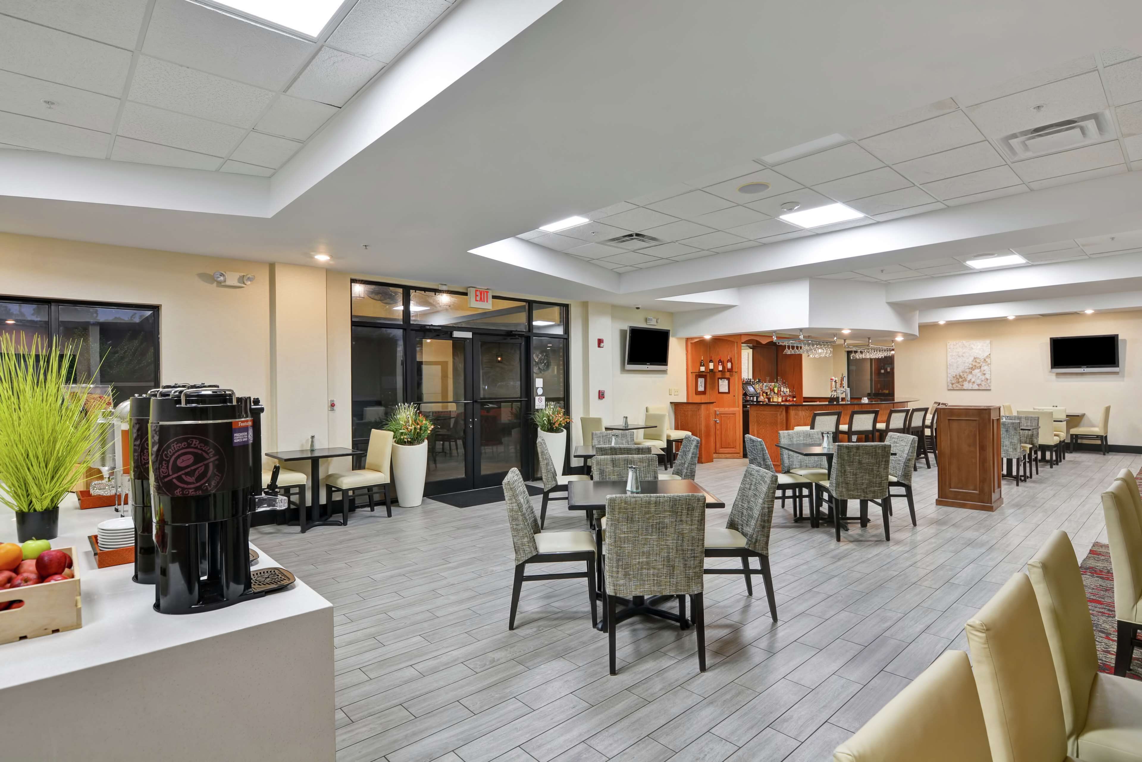A spacious dining area with multiple tables and chairs, a coffee station, and a bar area.