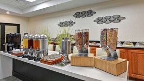 A buffet area with various food dispensers, including a coffee machine, a juice dispenser, and a cereal dispenser.