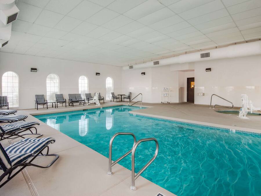 An indoor swimming pool with lounge chairs and a tiled floor.