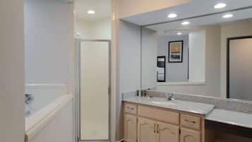 Une salle de bain moderne dotée d’une douche à parois de verre, d’un grand miroir et d’un meuble-lavabo avec un évier et un placard.
