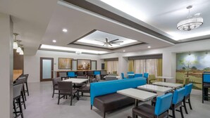 A modern dining area with high tables, blue booths, and a ceiling fan. - Wingate by Wyndham Memphis East (Memphis)