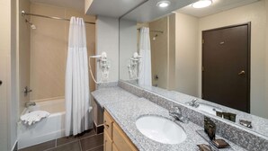 A modern bathroom with a large sink, mirror, and shower area. - Wingate by Wyndham Memphis East (Memphis)
