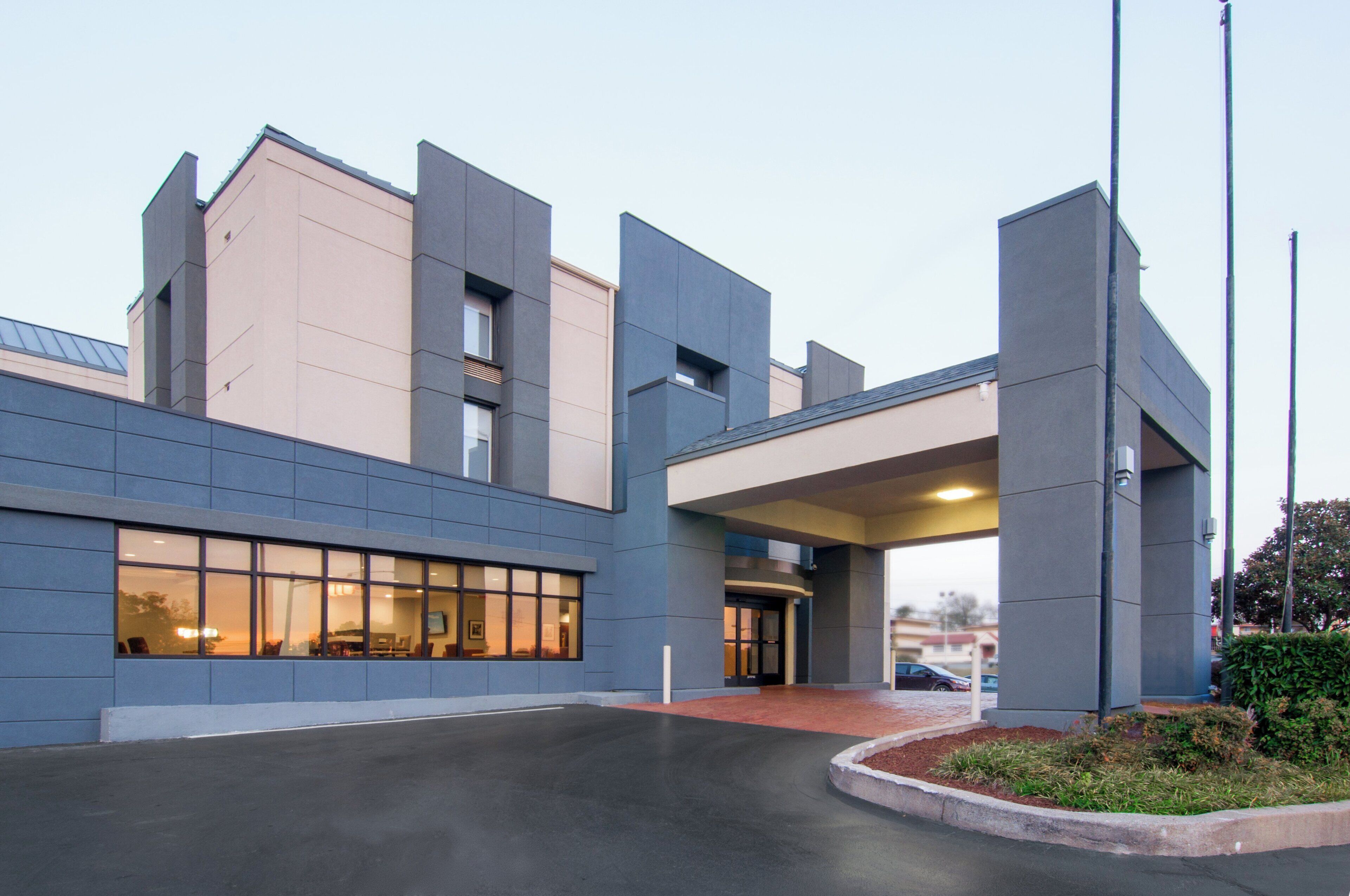 A modern building with a flat roof, large windows, and a covered entrance.
