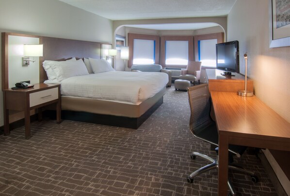 Een hotelkamer met een groot bed, een bureau, een stoel en een televisie.