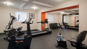 Un gimnasio con cintas de correr, elípticas y una máquina de remo.
