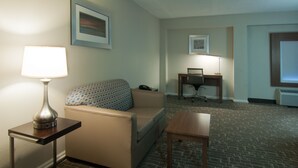A hotel room with a sofa, a small table, a lamp, a desk, and a chair. - Holiday Inn Express Hotel & Suites Spence Lane by IHG (Nashville)