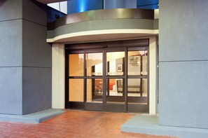 A hotel entrance with a curved facade, a glass door, and a brick-paved entrance area. - Holiday Inn Express Hotel & Suites Spence Lane by IHG (Nashville)