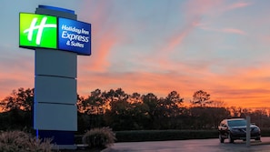 A Holiday Inn Express & Suites sign with a clear view of the surrounding landscape and a parked car. - Holiday Inn Express Hotel & Suites Spence Lane by IHG (Nashville)