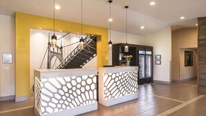 A reception area with a modern design, featuring a staircase, a reception desk, and a refrigerator. - La Quinta Inn & Suites by Wyndham Portland NW (Portland)