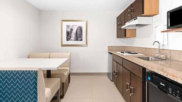 Una cocina moderna con comedor, que incluye lavavajillas, estufa y un cuadro en la pared.