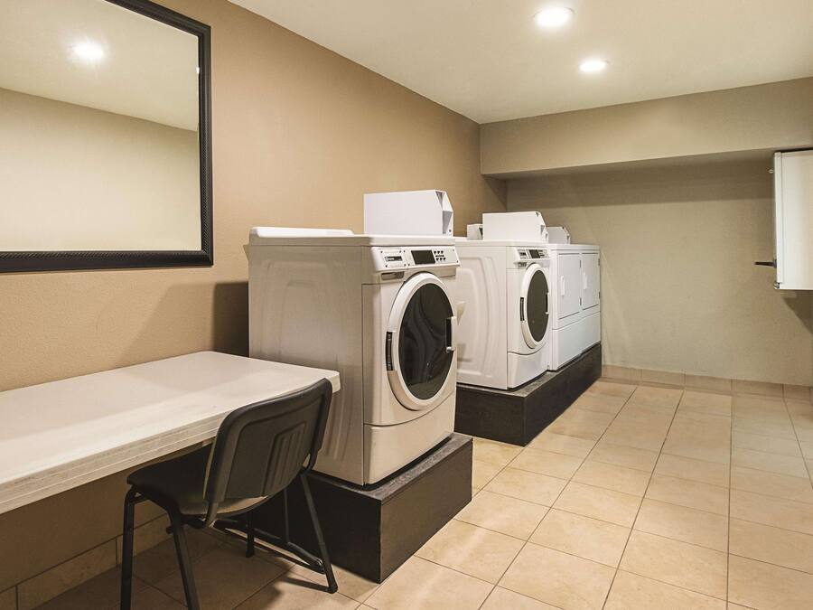 A laundry room with a washing machine, dryer, and a table with a chair.