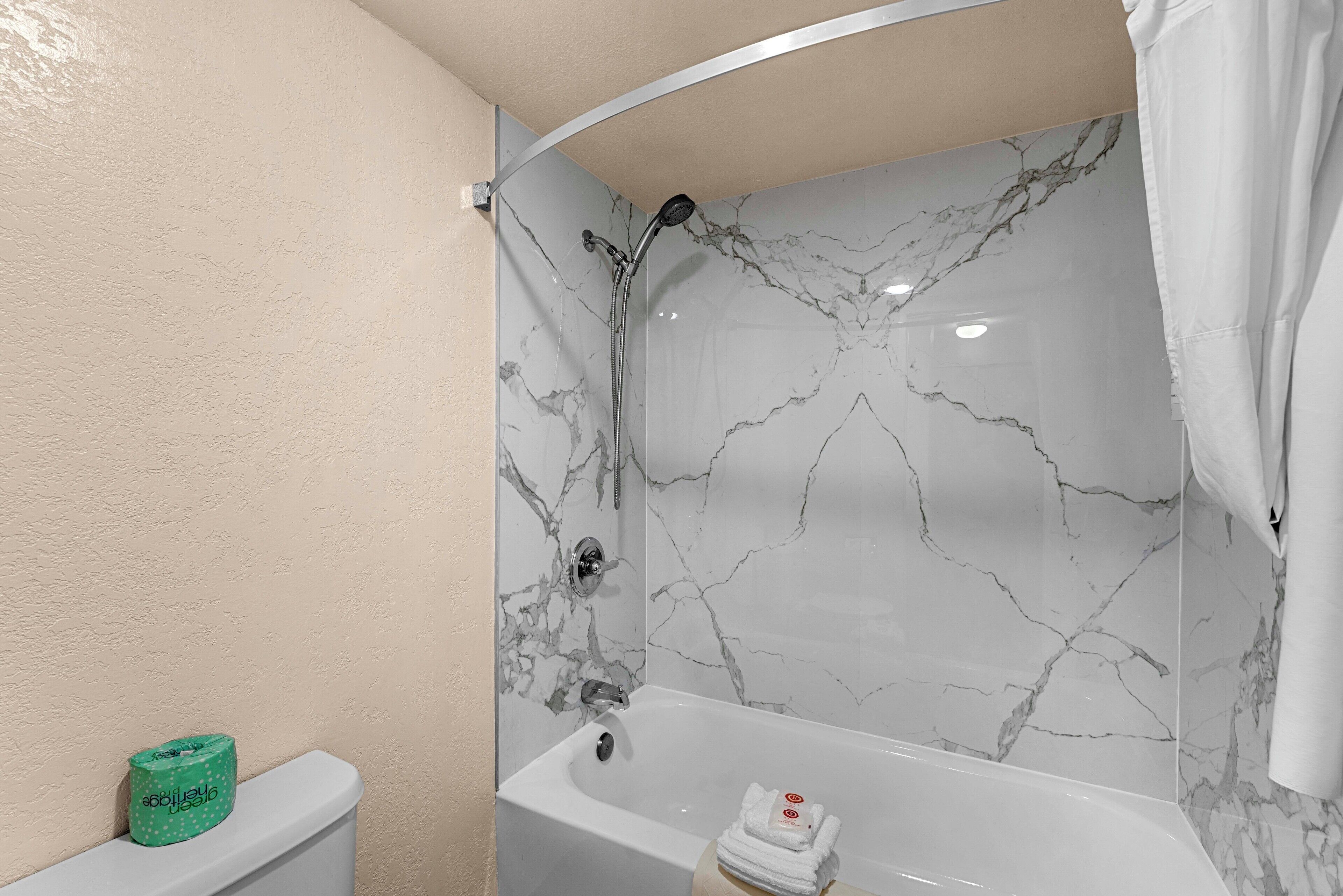 A bathroom with a white bathtub, a shower, and a toilet.