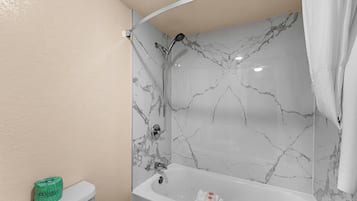 Un baño con una bañera blanca, ducha e inodoro.