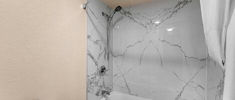 A bathroom with a white bathtub, a shower, and a toilet.