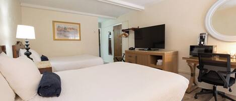 Habitación de hotel con una cama grande, un escritorio con ordenador, televisión y cafetera.