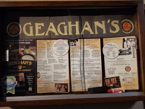 A menu board at Geaghan's Pub and Craft Brewery with various food and drink options listed.