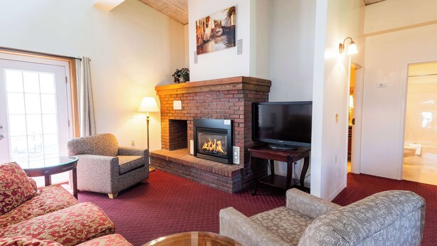 A cozy living room with a fireplace, comfortable seating, and a television. - Fireside Inn & Suites Bangor (Bangor)
