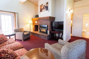 Un salon chaleureux avec une cheminée, des fauteuils confortables et un téléviseur.