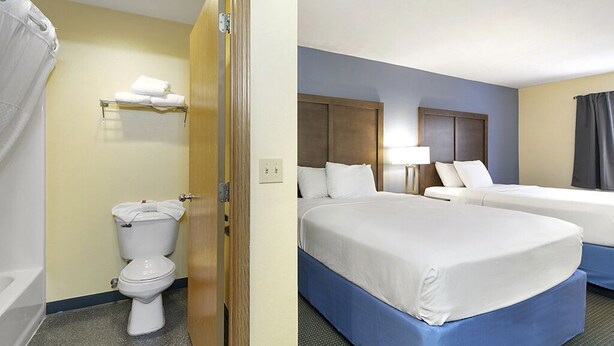 Ett hotellrum med toalett, säng, sängbord och en lampa.