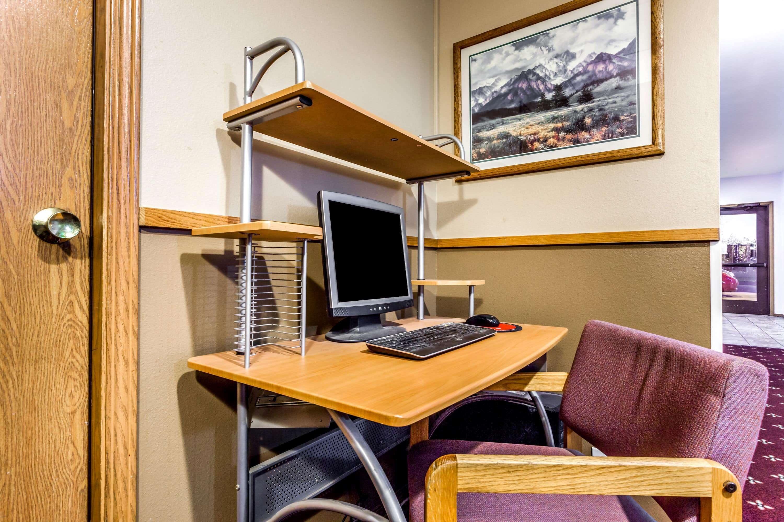 A compact workspace with a wooden desk, a computer, and a cushioned chair.