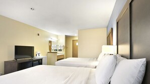 Habitació d'hotel amb dos llits, una televisió, escriptori amb cafetera i un mirall.