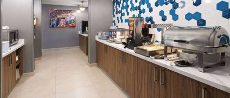 Una cocina moderna con estación de café, microondas y parrilla.