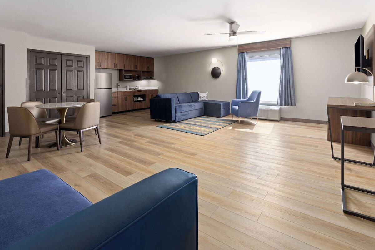 A modern apartment with a dining area, kitchen, living room, and a large window.