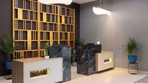 A reception area with two reception desks, a modern wooden partition, and potted plants. - La Quinta Inn & Suites by Wyndham Memphis I-240 (Memphis)