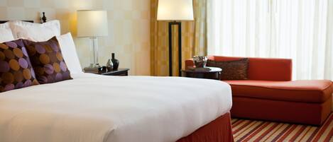 A hotel room with a large bed, a red sofa, a lamp, and a checkered wall.