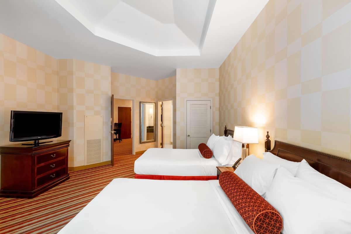 A hotel room with two beds, a television, a desk, and a lamp.