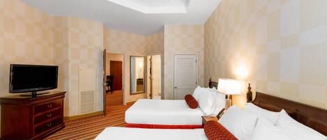 A hotel room with two beds, a television, a desk, and a lamp.