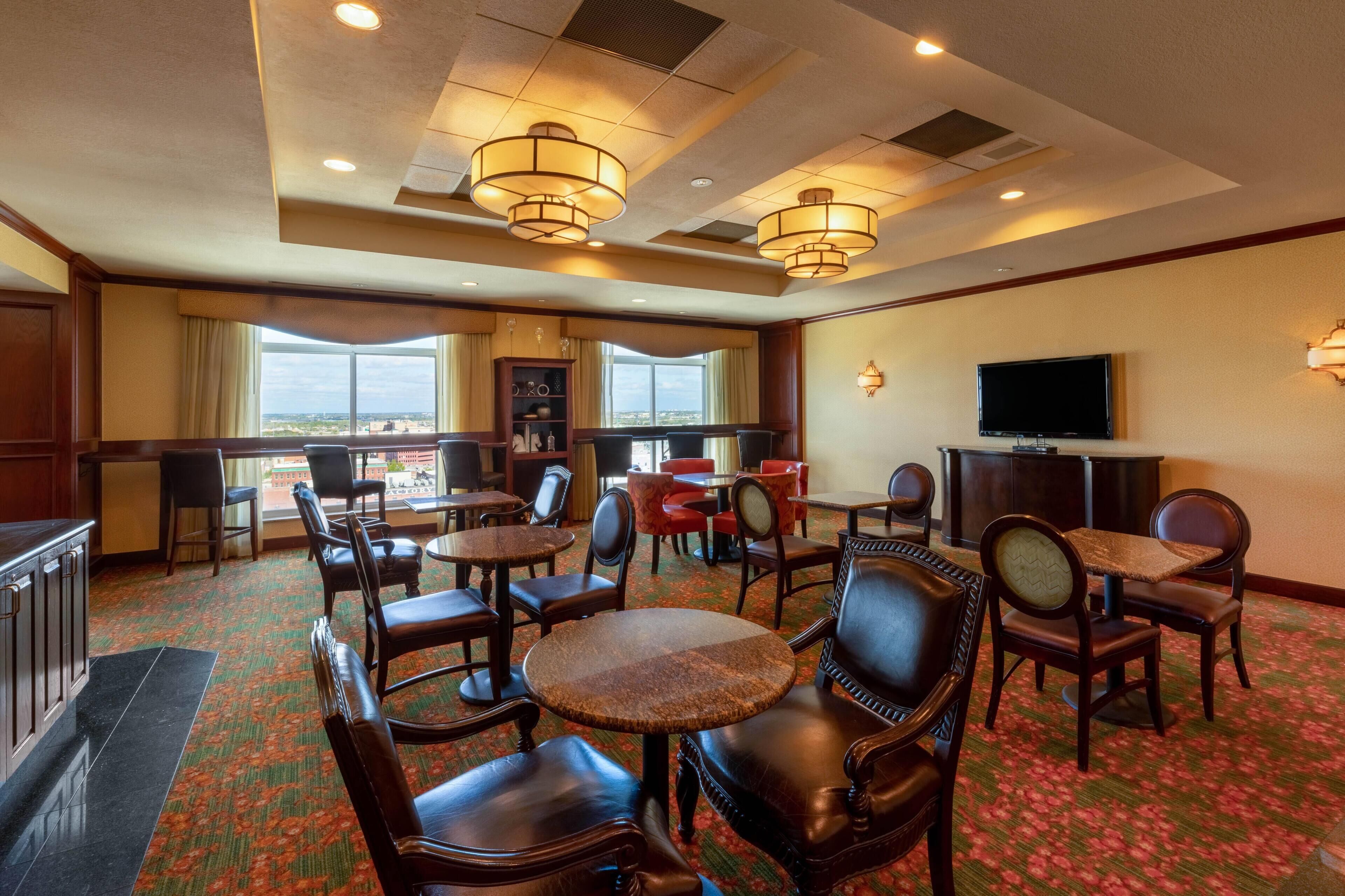 A hotel lobby with multiple seating areas, a television, and a view through large windows.