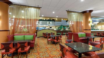 A hotel lobby with red seating, tables, and a patterned carpet.