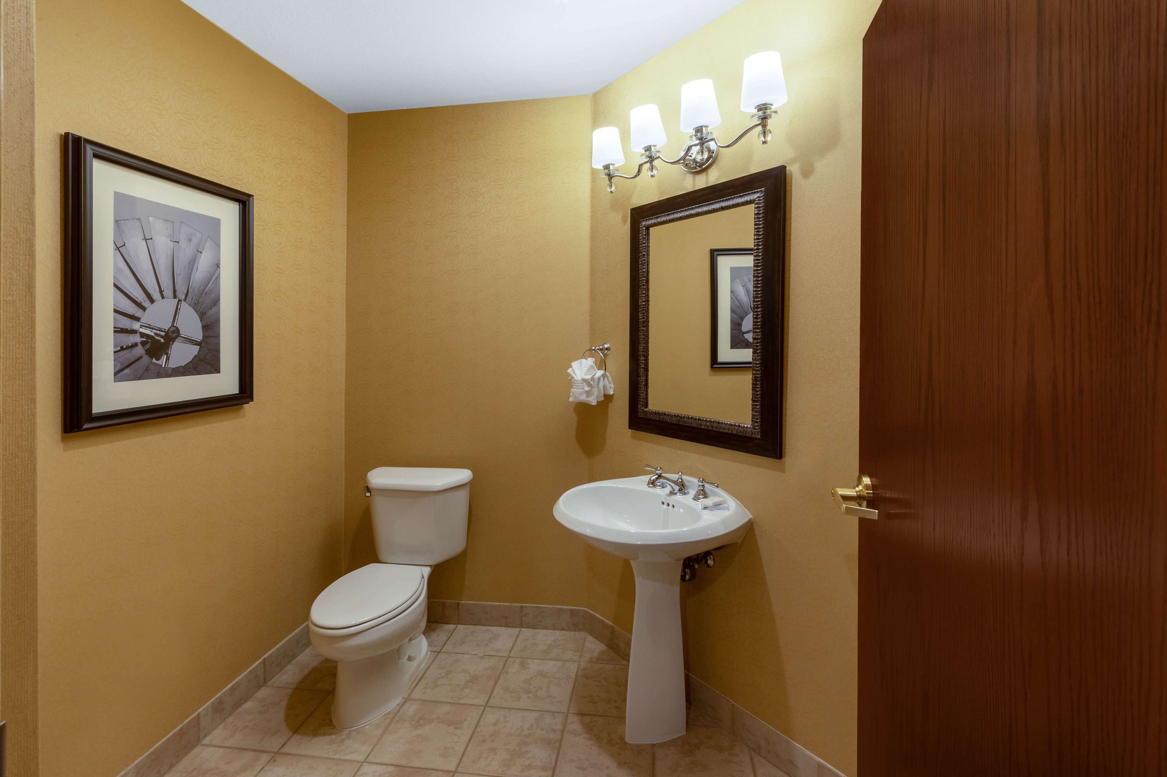 A bathroom with a toilet, sink, and mirror.