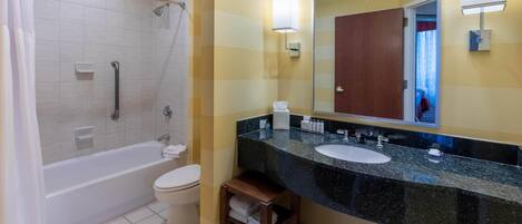 Een badkamer met een badkuip, toilet, wastafel en een grote spiegel.