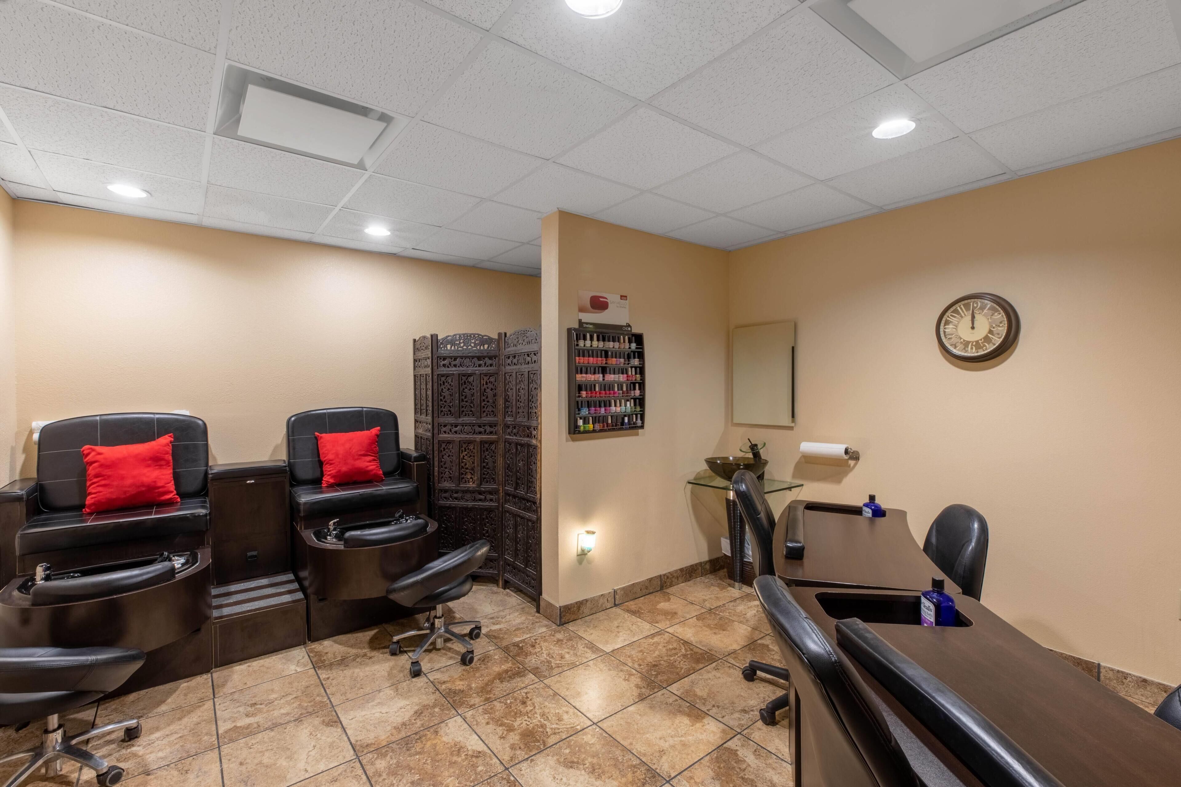 A room with two massage chairs, a reception desk, a clock, and a shelf with various items.