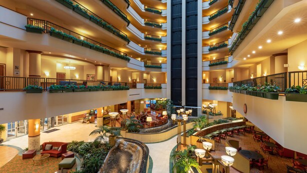 Un vestíbulo de hotel de varios niveles con un atrio central, múltiples balcones y zonas de estar interiores.