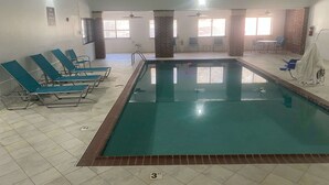 Une piscine intérieure avec des chaises longues et une pièce lumineuse, dotée de tables et de chaises.