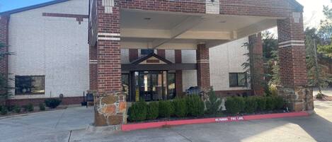 A building with a covered entrance, brick facade, and a fire lane.