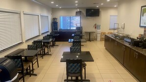 Un restaurant doté de plusieurs tables et chaises, d’un téléviseur fixé au mur et d’un distributeur d’eau.