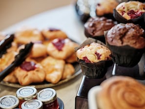 A variety of baked goods, including muffins and pastries, arranged on a tray and in paper cups.